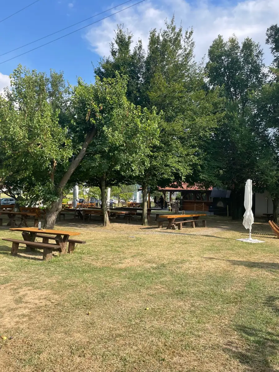 Giardino di Agri-K con tavoli in legno all'ombra degli alberi